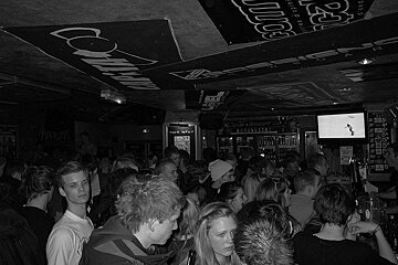 A black and white photo of a crowded bar with a sign that says ' columbia ' on it