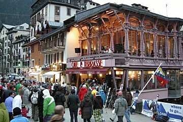 A crowd of people are gathered outside a restaurant called cafe a terrasse
