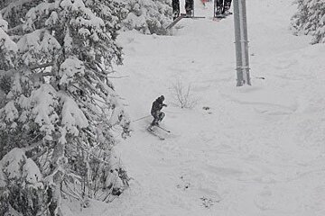 Skiers on a ski lift with a sign that says ' a ' on it