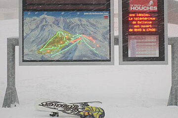A snowboard is laying on the ground in front of a sign that says la vette houches