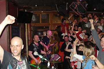 A man in a black shirt with a skull on it sings into a microphone