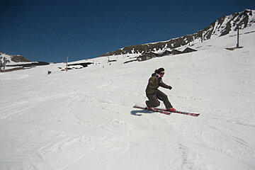 A person skiing down a snow covered slope with the word ross on their skis