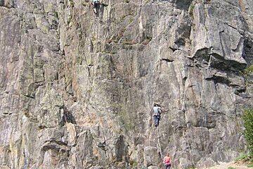 Two people are climbing up a rock wall