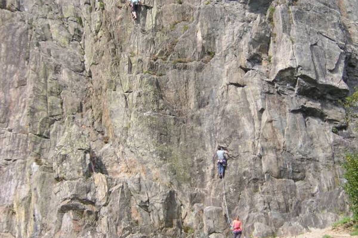 Two people are climbing up a rock wall