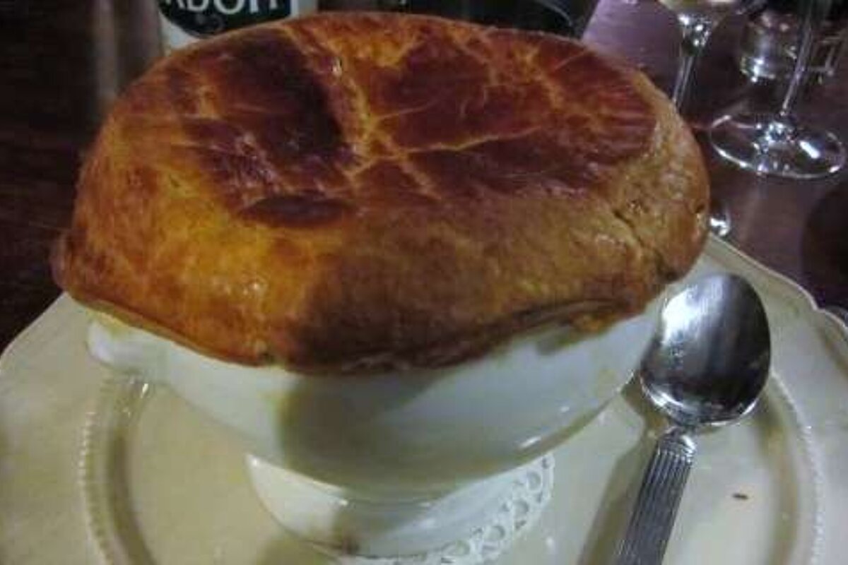 A bowl of pot pie is on a plate with a spoon