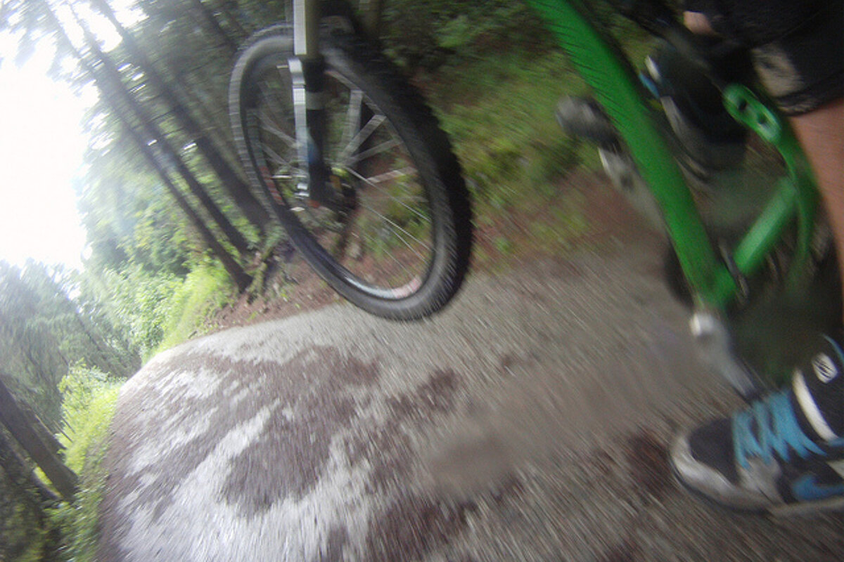 A person is riding a green bike on a dirt path