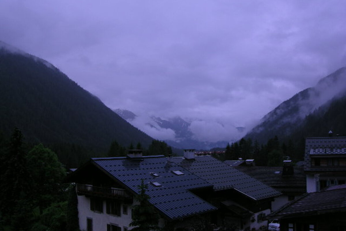 A purple sky with mountains in the background and houses in the foreground