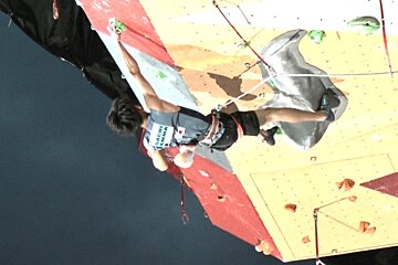 A man is climbing a wall with a shirt that says ' tachi ' on it