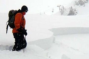 an image of a man standing next to the top of an avalanche site