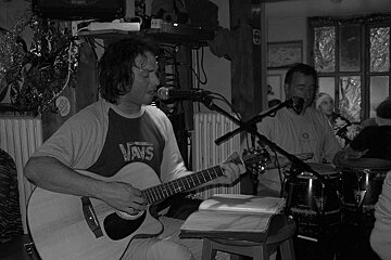 A man in a vans shirt is playing a guitar