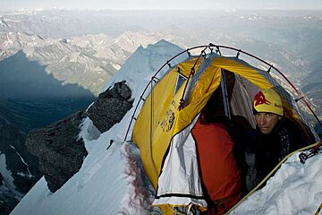 A man wearing a red bull hat sits in a tent