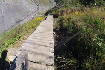 A bicycle tire is on the side of a wooden bridge