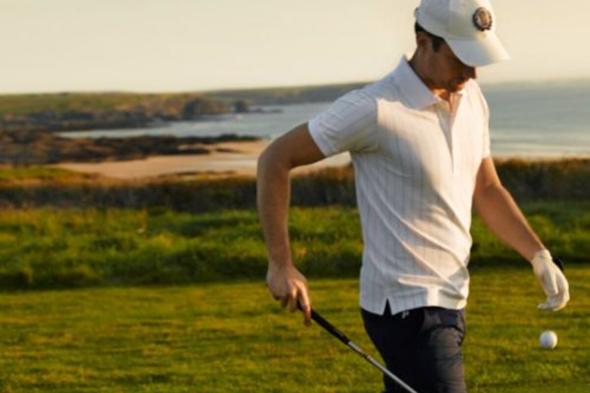 A man is holding a golf club and a golf ball on a golf course