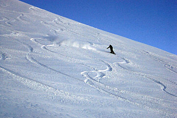 A person riding a snowboard down a snowy hill