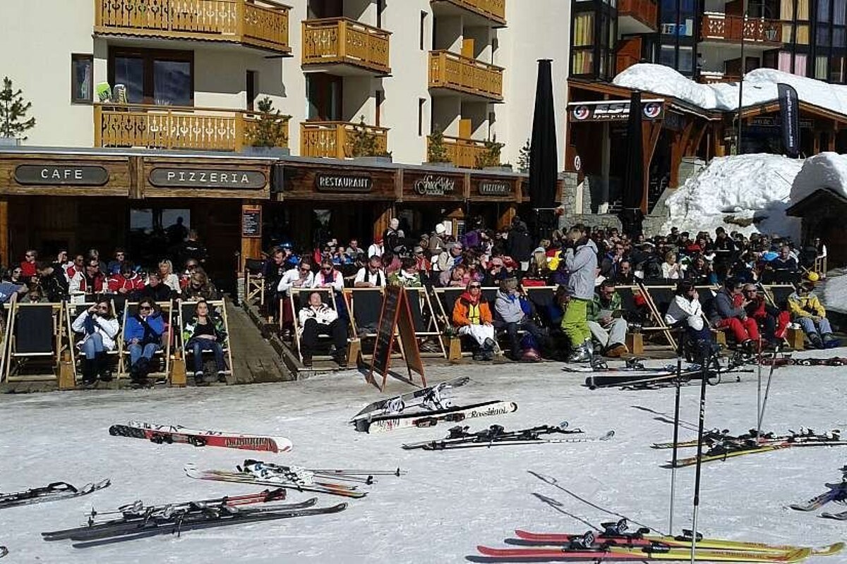 A group of people sit outside a restaurant called pizzeria