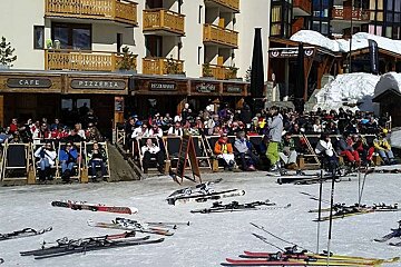 A group of people sit outside a restaurant called pizzeria