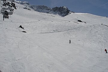 Skiers on a snowy slope with a ski lift in the background