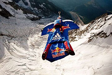 A person is flying through the air wearing a red bull outfit