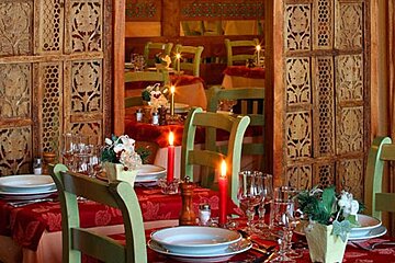 A dining room with plates glasses and candles on the tables