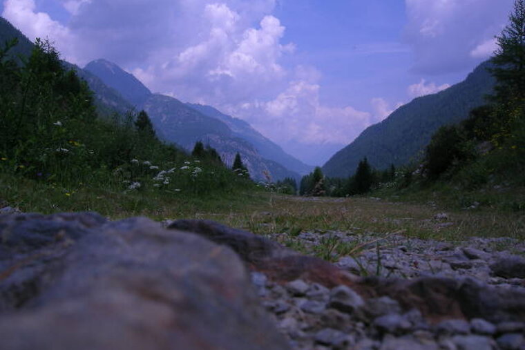 A valley with mountains in the background and a rock in the foreground