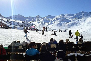 A group of people are sitting in chairs in front of a snowy mountain