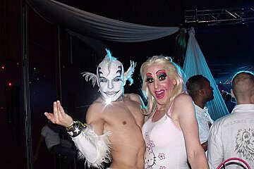 A woman in a hello kitty shirt poses with a man in a white mask