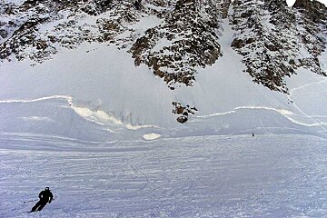 A person skiing down a snowy slope with mountains in the background