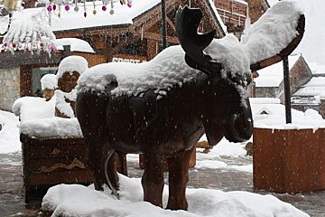 A picture of a wooden moose covered in snow