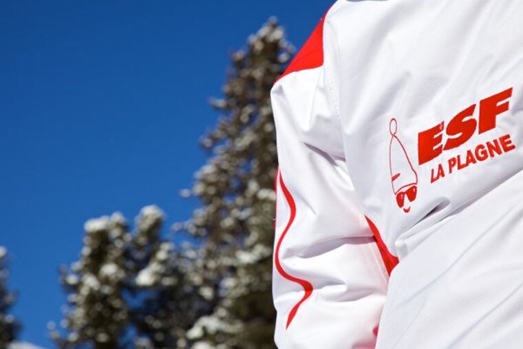 A person wearing a white and red jacket that says esf la plagne