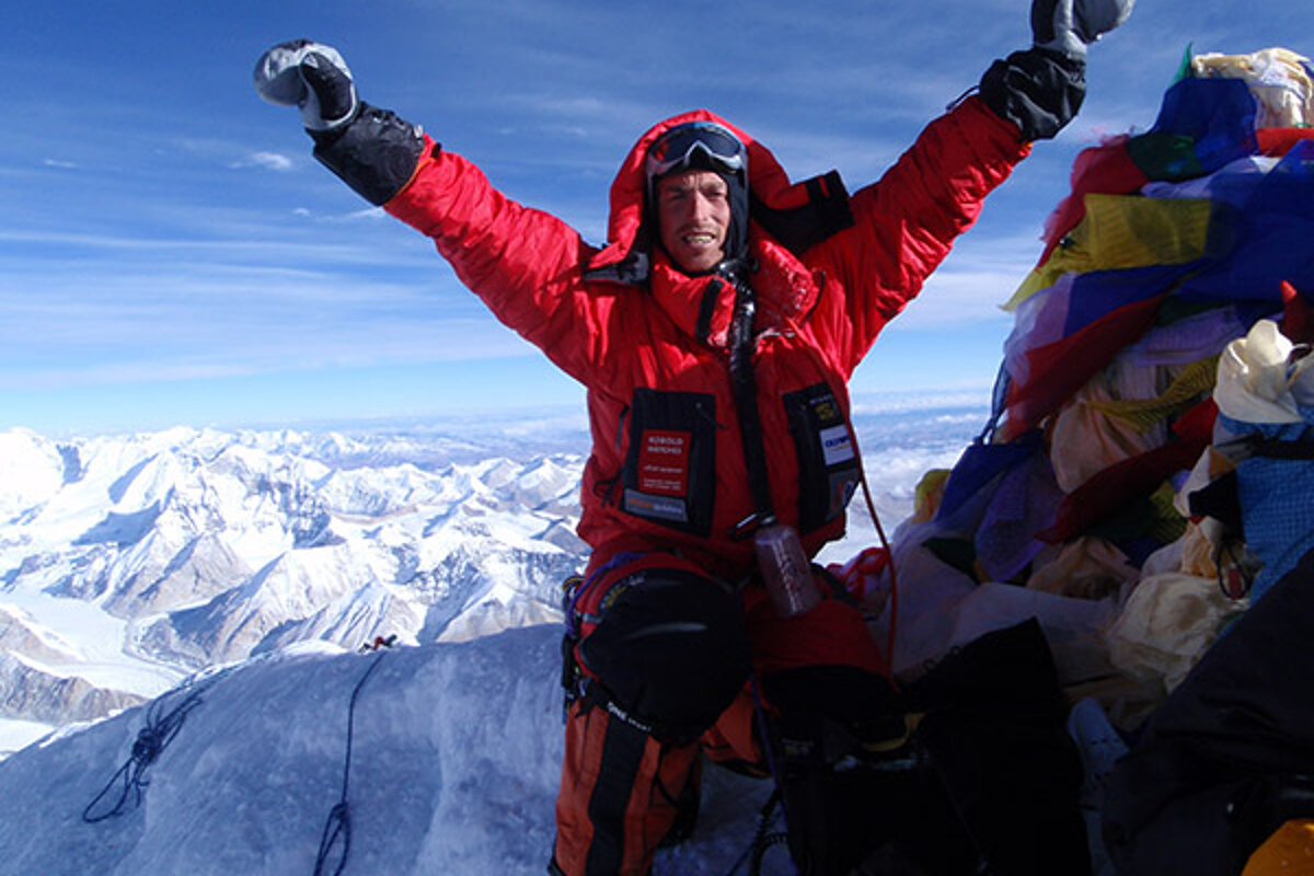 A man in a red jacket with a pocket that says ' expedition ' on it