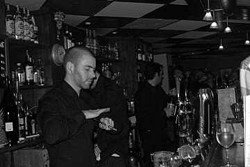 A bartender prepares a drink with a bottle of ketel one in the background