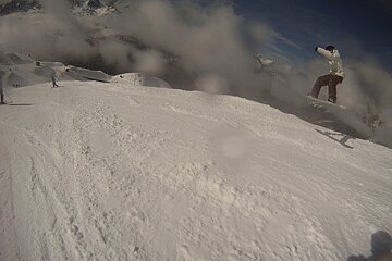 A snowboarder is doing a trick on top of a snow covered slope