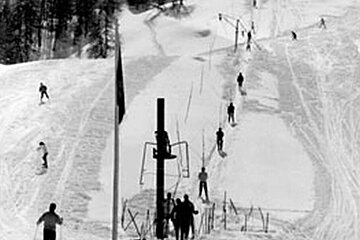A black and white photo of people skiing down a snow covered slope