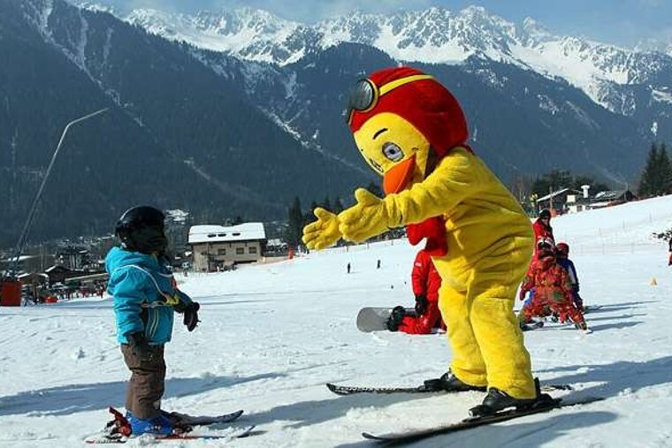 child skiing with instructor dressed as Piou Piou