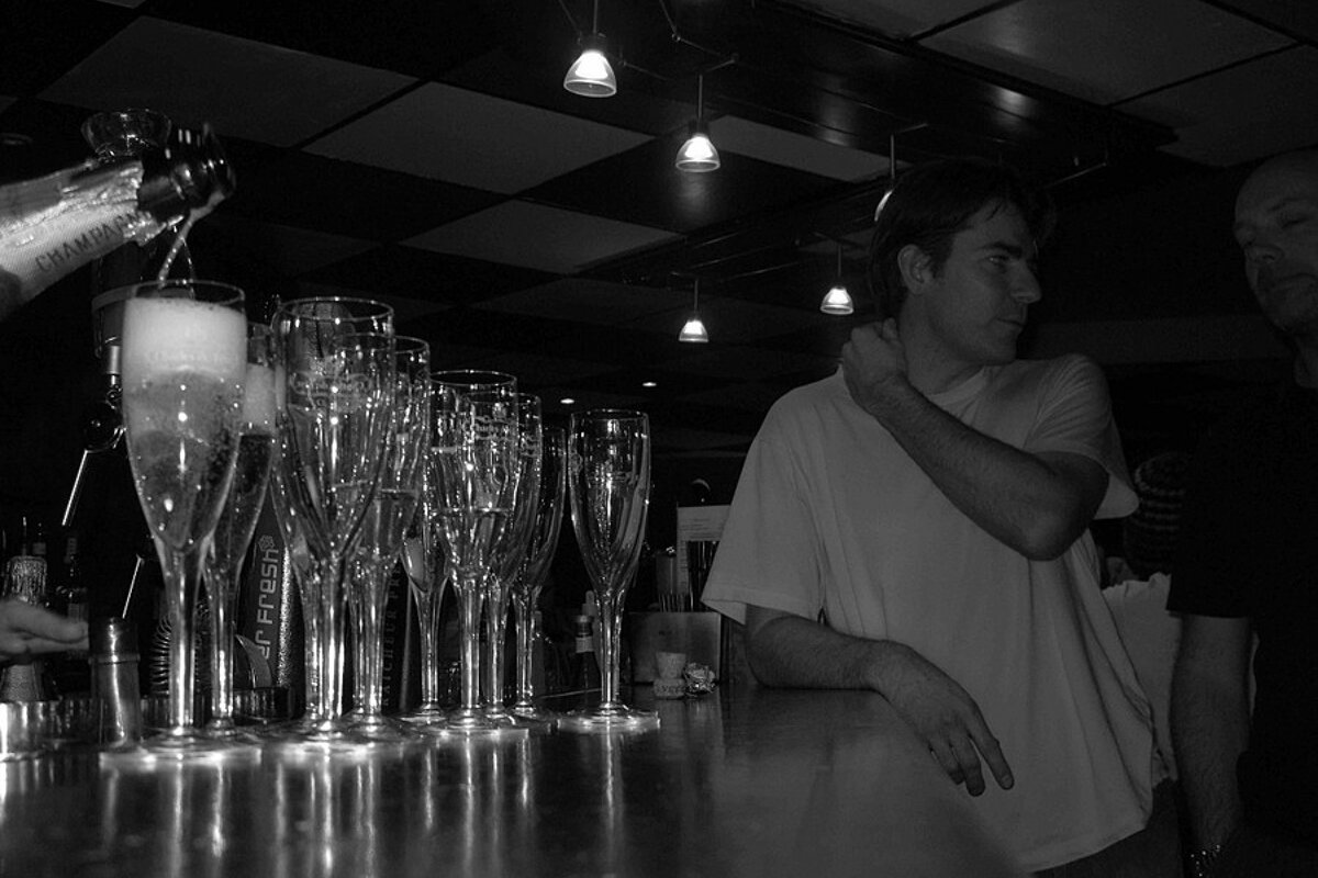 A bartender pours champagne into a row of glasses that say 