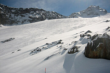 A snowy mountain with a red pole in the foreground