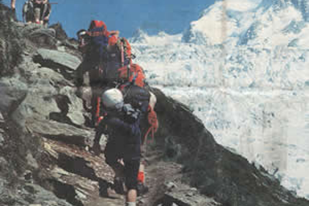 A group of people with backpacks are hiking up a mountain