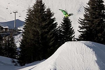 A snowboarder is doing a trick on a snowy ramp