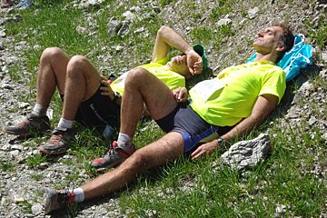 Two men are laying on the ground and one has a tag on his shirt that says ' salomon ' on it
