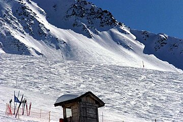 A snowy mountain with a small hut in the foreground