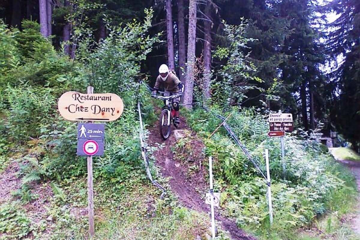 A person riding a bike in the woods near a restaurant sign
