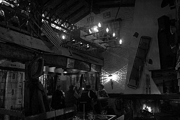A black and white photo of a restaurant with people sitting at tables