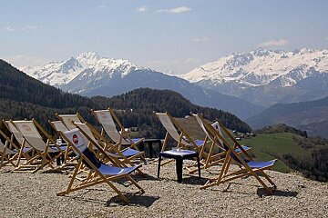 An image of deckchairs, snow capped mountains and summer at a restaurant in the ski resort of Montalbert in the French Alps