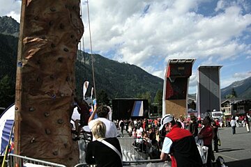 A man climbs a climbing wall while a crowd watches