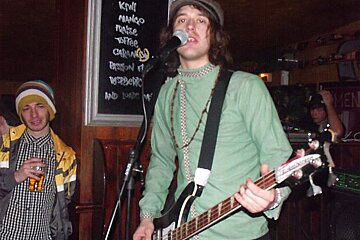 A man playing a guitar in front of a sign that says pineapple