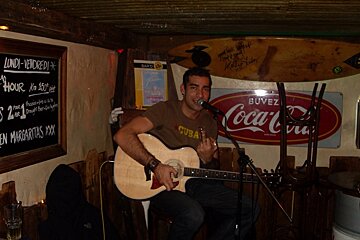 A man singing into a microphone in front of a coca cola sign