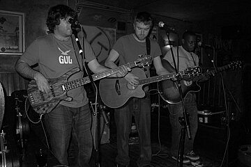 A man wearing a shirt that says gul is playing a guitar