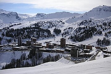 A ski resort is surrounded by snow covered mountains