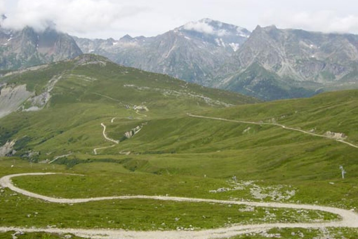 A dirt road in the mountains with mountains in the background