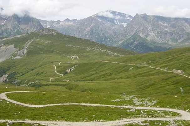 A dirt road in the mountains with mountains in the background